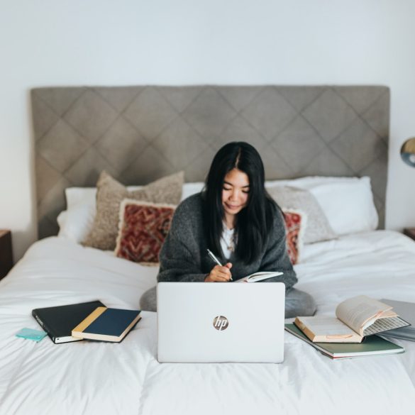 woman in black hijab sitting on bed using laptop